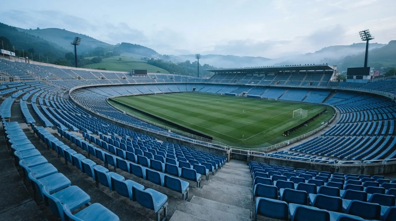 Ein leeres Stadion im Morgenlicht mit Blick auf die Sitzreihen, im Hintergrund Hügel und aufsteigender Nebel.