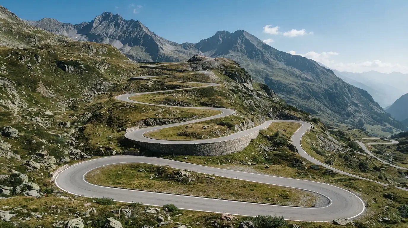 Eine Passstrasse zieht sich in Kehren einen Alpenhang hinauf, kein Fahrzeug ist zu sehen.